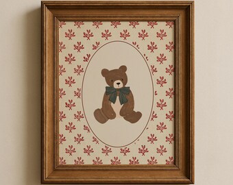 May include: A framed wall art print featuring a brown teddy bear with a dark green bow tie centered inside an oval border. The background is a cream-colored paper with a repeating pattern of small red sprigs, all encased in a wooden frame.