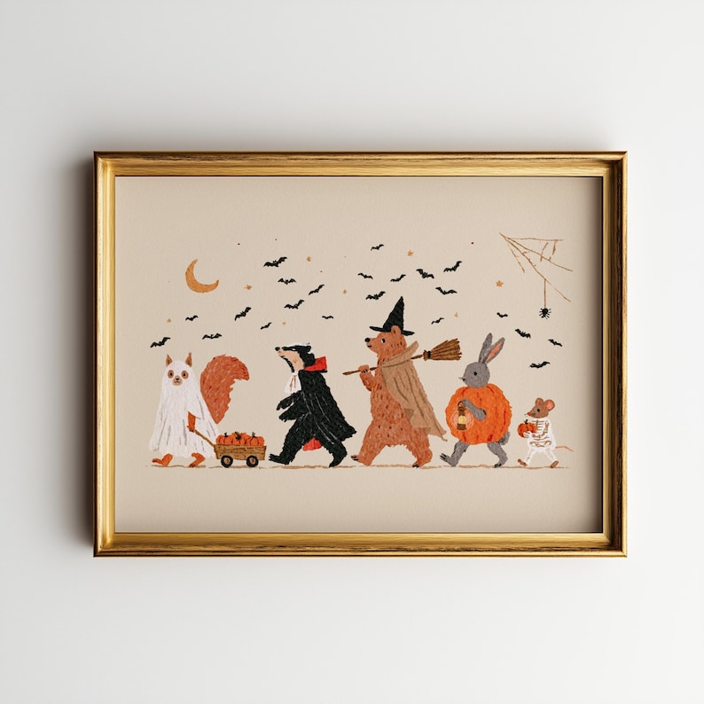 May include: A framed horizontal art print featuring a line of five animals in Halloween costumes: a squirrel as a ghost pulling a pumpkin wagon, a badger in a cape, a bear as a witch, a rabbit in a pumpkin suit, and a mouse in a skeleton suit.