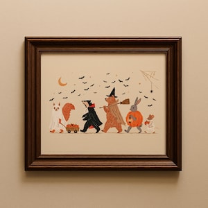 May include: A framed illustration featuring a squirrel in a ghost costume pulling a wagon of pumpkins, a badger in a black cape, a bear in a witch hat with a broom, a rabbit in a pumpkin suit, and a mouse in a skeleton costume under bats.