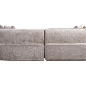 Puede incluir: Sof&aacute; de dos piezas de color gris claro con tejido texturizado. El sof&aacute; tiene forma redondeada con respaldo bajo y reposabrazos. La parte trasera del sof&aacute; tiene dos peque&ntilde;os cojines decorativos. El sof&aacute; est&aacute; sobre un fondo blanco.