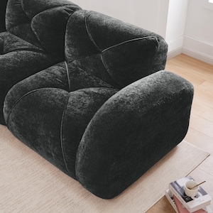May include: A dark charcoal gray sofa featuring a plush, textured velvet-like fabric with deep, tufted geometric stitching patterns across the seat and back cushions, creating a soft, rounded, and modular appearance with thick, padded armrests.