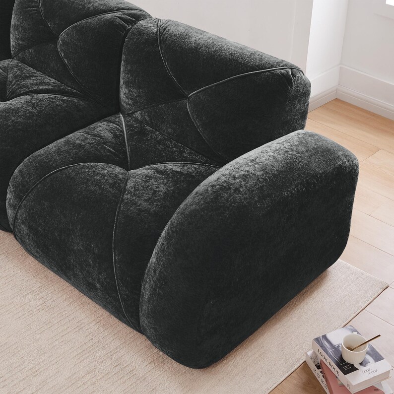 May include: A dark charcoal gray sofa featuring a plush, textured velvet-like fabric with deep, tufted geometric stitching patterns across the seat and back cushions, creating a soft, rounded, and modular appearance with thick, padded armrests.
