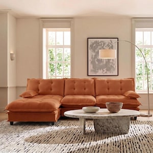 May include: An orange sectional sofa with tufted cushions and a chaise lounge. A round marble coffee table with a woven basket and a bowl sits on a patterned rug. A floor lamp and artwork complete the living room setting.