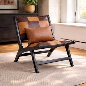 May include: A modern accent chair with a black wooden frame and a seat and backrest made of brown leather squares. A matching leather pillow rests on the seat. The chair is designed for indoor use.