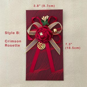 Puede incluir: Sobre rojo carmes&iacute;, de 9,7 cm de ancho y 18,5 cm de alto, con una roseta decorativa y detalles dorados. El sobre presenta una cinta roja, un dije dorado y un adorno floral. El texto "Style B: Crimson Rosette" es visible.