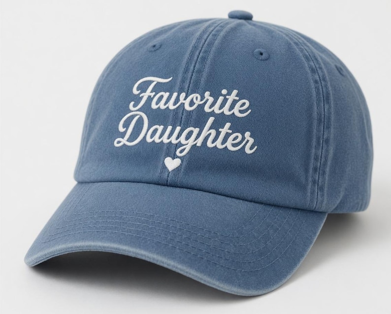 Puede incluir: Gorra de b&eacute;isbol azul con las palabras "Favorite Daughter" en escritura blanca y un peque&ntilde;o coraz&oacute;n blanco. La gorra tiene una visera curva y un bot&oacute;n en la parte superior.