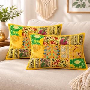 May include: Two rectangular throw pillows featuring a vibrant patchwork design in shades of yellow, green, and gold. The fabric displays intricate embroidery, sequin embellishments, and paisley patterns, finished with a solid yellow border trim.
