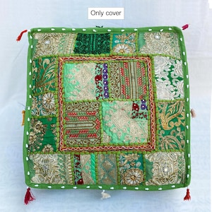 K&ouml;nnte beinhalten: Quadratische gr&uuml;ne Kissenh&uuml;lle mit Patchwork-Design. Die H&uuml;lle zeigt verschiedene Gr&uuml;nt&ouml;ne, Gold und Rot mit aufwendigen Stickereien und Verzierungen. Die Kanten sind mit einem gr&uuml;nen Rand und kleinen Quasten versehen.