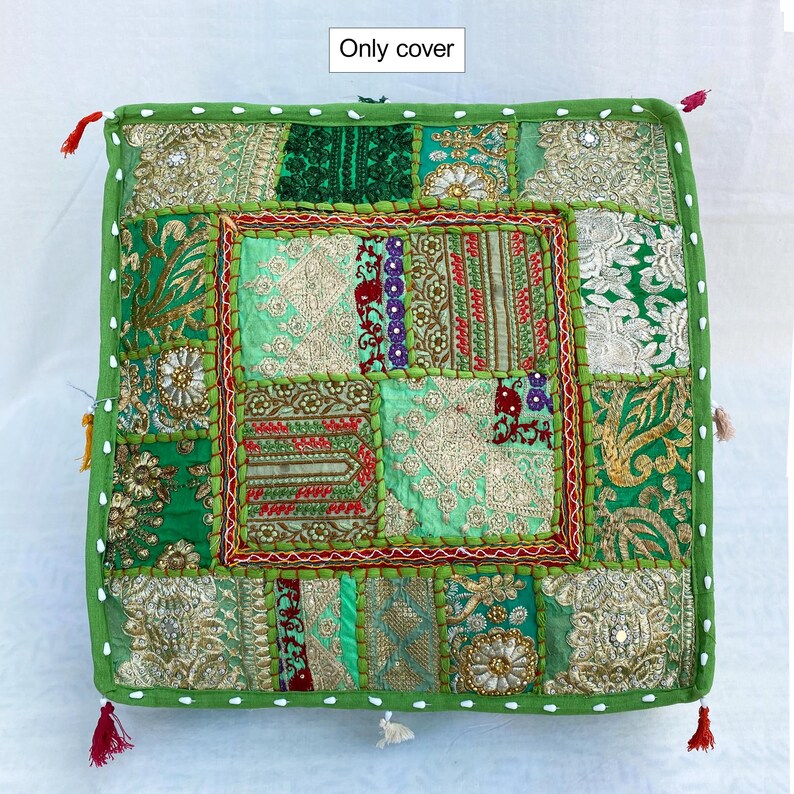K&ouml;nnte beinhalten: Quadratische gr&uuml;ne Kissenh&uuml;lle mit Patchwork-Design. Die H&uuml;lle zeigt verschiedene Gr&uuml;nt&ouml;ne, Gold und Rot mit aufwendigen Stickereien und Verzierungen. Die Kanten sind mit einem gr&uuml;nen Rand und kleinen Quasten versehen.