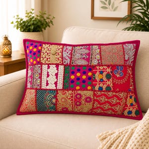 May include: A rectangular throw pillow featuring a vibrant patchwork design of various fabrics. The surface displays a mix of bright pink, gold, teal, and white textiles with intricate embroidery, sequins, and colorful polka dot patterns.