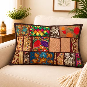 May include: A rectangular throw pillow featuring a patchwork design of various embroidered fabrics. The surface displays a mix of floral patterns, geometric shapes, and metallic thread accents in vibrant colors like red, blue, green, and gold.