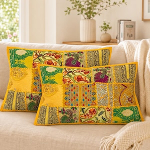 May include: Two rectangular throw pillows featuring a vibrant patchwork design with yellow, green, and purple fabric panels. The pillows are decorated with intricate embroidery, metallic thread accents, and detailed floral and peacock motifs.