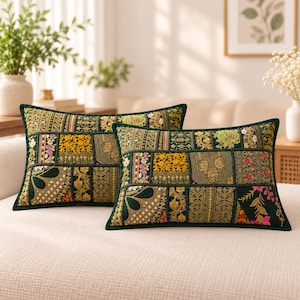 May include: Two rectangular throw pillows featuring a dark green velvet base with a patchwork design of embroidered panels. The embroidery includes gold, yellow, pink, and green floral and geometric patterns with metallic thread accents.