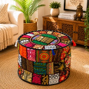 Peut inclure: Un pouf de sol rond présentant un design en patchwork composé de divers tissus colorés, de broderies complexes et d'accents de fils métalliques. Le dessus et les côtés sont ornés de motifs variés, de petits pompons et d'un liseré noir.