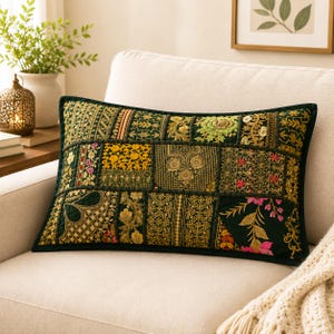 May include: A rectangular throw pillow featuring a dark green base with a patchwork design of intricate gold, yellow, and pink floral embroidery. The fabric displays various ornate patterns, including geometric shapes, botanical motifs, and decorative borders.