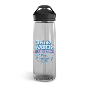 Può includere: Borraccia trasparente con coperchio e manico neri. La borraccia ha una cannuccia e una grafica che dice "Drink WATER ALL THE TIME Pee, Occasionally" in lettere blu e rosa. Il marchio "Camelbak" è stampato sul coperchio.
