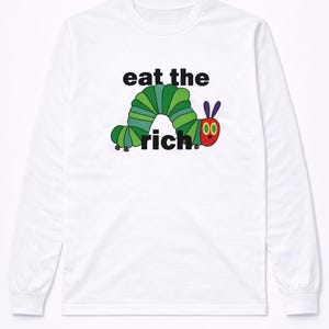 Könnte beinhalten: Weißes Langarmshirt mit einem Cartoon-Raupen-Design und dem Text "eat the rich". Die Raupe ist grün, rot und schwarz. Das Shirt ist ein lässiger Stil.