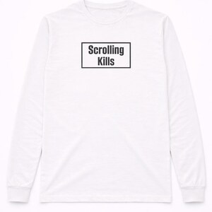 May include: White long-sleeve shirt with the text "Scrolling Kills" in a black rectangular box on the front. The shirt has a crew neck and long sleeves. The text is in a bold, sans-serif font.