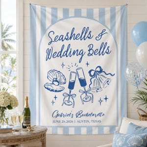 Könnte beinhalten: Ein weiß-blau gestreifter Wandteppich mit dem Text "Seashells & Wedding Bells" in Marineblau. Der Wandteppich zeigt Illustrationen einer Muschel, Champagnergläser und Glocken. Der Text "Gabriel's Bachelorette" ist ebenfalls enthalten.