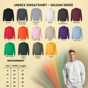 Op de afbeelding: Een display van Gildan 18000 unisex sweatshirts in diverse kleuren, waaronder zwart, rood en goud. De afbeelding bevat een maattabel van S tot 2XL, met breedtes van 50.8 tot 71.1 cm en lengtes van 68.6 tot 78.7 cm.