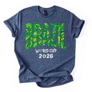 May include: A blue t-shirt with the word "BRAZIL" in large green and yellow letters, filled with tropical patterns. Below, the text reads "WORLD CUP 2026" with soccer ball graphics.