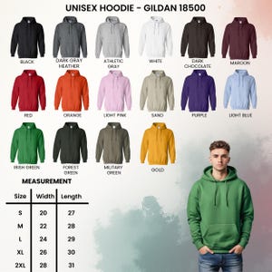 Op de afbeelding: Een display van unisex hoodies in diverse kleuren, waaronder zwart, grijs en rood. De afbeelding bevat een maattabel met afmetingen in centimeters. De tekst bovenaan luidt "UNISEX HOODIE - GILDAN 18500".