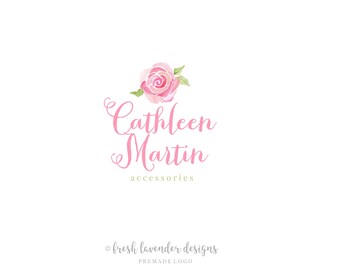 Może przedstawiać: Projekt logo w akwareli z różową różą i zielonymi liśćmi. Tekst "Cathleen Martin accessories" jest napisany różowym pismem ozdobnym pod różą. Tekst "fresh lavender designs PREMADE LOGO" jest napisany szarym kolorem pod logo.