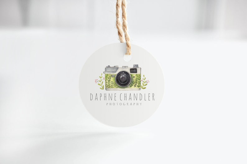May include: A round white tag with a green and white camera illustration and the text "Daphne Chandler Photography".