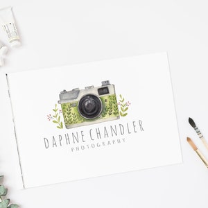 May include: A watercolor illustration of a vintage camera with green and white floral details. The text "Daphne Chandler Photography" is written below the camera.