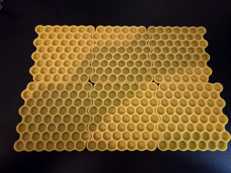May include: Six yellow silicone mats arranged in a grid, each featuring a repeating hexagonal honeycomb pattern with circular indentations. The mats are uniform in color and design, creating a textured surface with a consistent geometric layout.