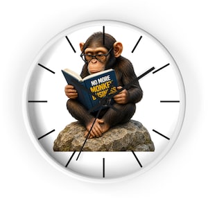 May include: A round white wall clock featuring a chimpanzee wearing black glasses, sitting on a rock and reading a blue book with the text NO MORE MONKEY BUSINESS printed in yellow. The clock has black hour markers and black clock hands.