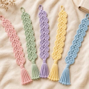 May include: Five crochet bookmarks in pastel colors including pink, light green, lavender, yellow, and light blue. Each bookmark features a scalloped edge pattern, a small loop at the top, and a matching yarn tassel attached at the bottom end.