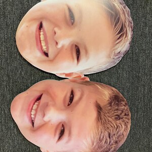Puede incluir: Dos recortes de cart&oacute;n de caras de ni&ntilde;os sonrientes. Los recortes est&aacute;n impresos con fotos de las caras de los ni&ntilde;os.