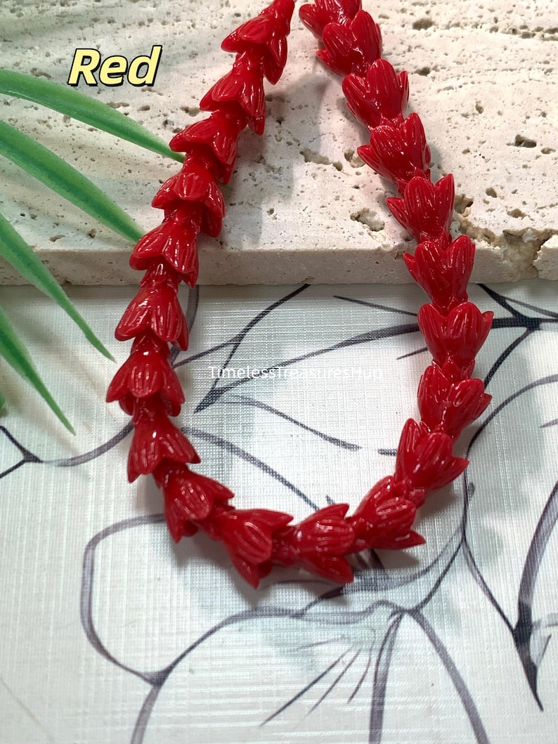 May include: A strand of bright red beads, each carved into the shape of a small, closed flower bud. The beads are arranged in a curved line, showcasing a glossy finish and uniform design. The text Red and TimelessTreasuresMug are visible.