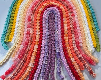 May include: A colorful rainbow-shaped beaded art piece. The beads are arranged in a gradient of colors, from red to purple, orange, yellow, green, and blue. The beads are strung together to form a decorative item.