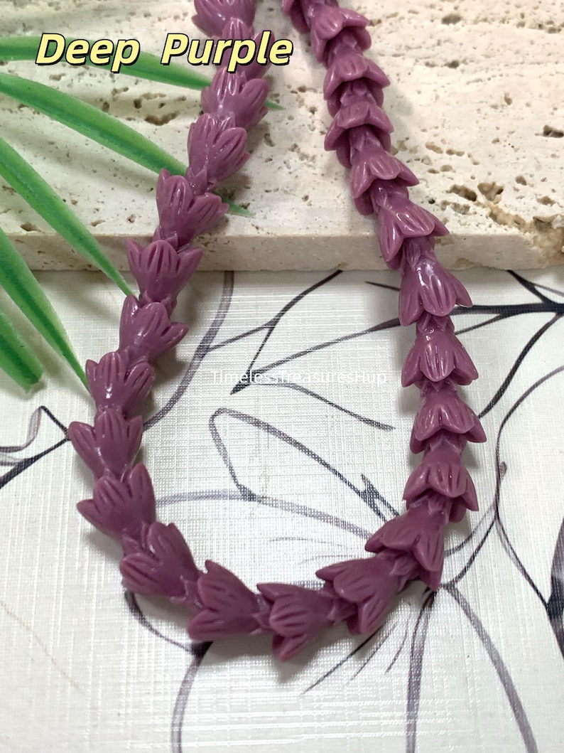 May include: A strand of deep purple beads shaped like small flower buds. The beads are arranged in a curved line. The text Deep Purple is visible at the top left, and the text TimelessTreasuresHup is visible in the center of the image.