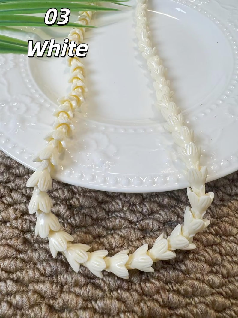 May include: A necklace composed of numerous off-white, flower-shaped beads strung together in a continuous strand. The beads feature a smooth, glossy finish and are arranged in a repeating pattern, creating a uniform, textured appearance throughout.