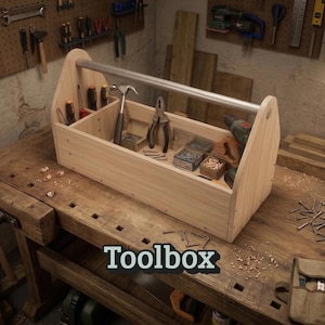 May include: A wooden toolbox with a metal handle, filled with various tools including a hammer, pliers, and screwdriver. The word "Toolbox" is displayed in a black font. The toolbox is sitting on a wooden workbench.