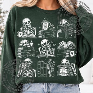 May include: A dark green crewneck sweatshirt featuring a white graphic print of nine distinct scenes with skeletons reading books, drinking from mugs, and flowers. The text includes Good Books Good Days, A well-read soul never fades, and Same Girl More Books.