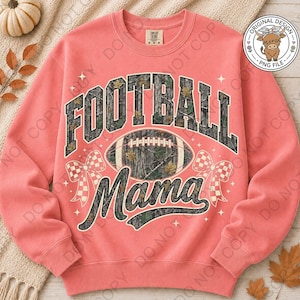 May include: A coral-colored crewneck sweatshirt featuring a graphic print with the text FOOTBALL MAMA in a camouflage pattern. The design includes a central football, two checkered bows, and small star accents. A circular logo with a highland cow is visible.