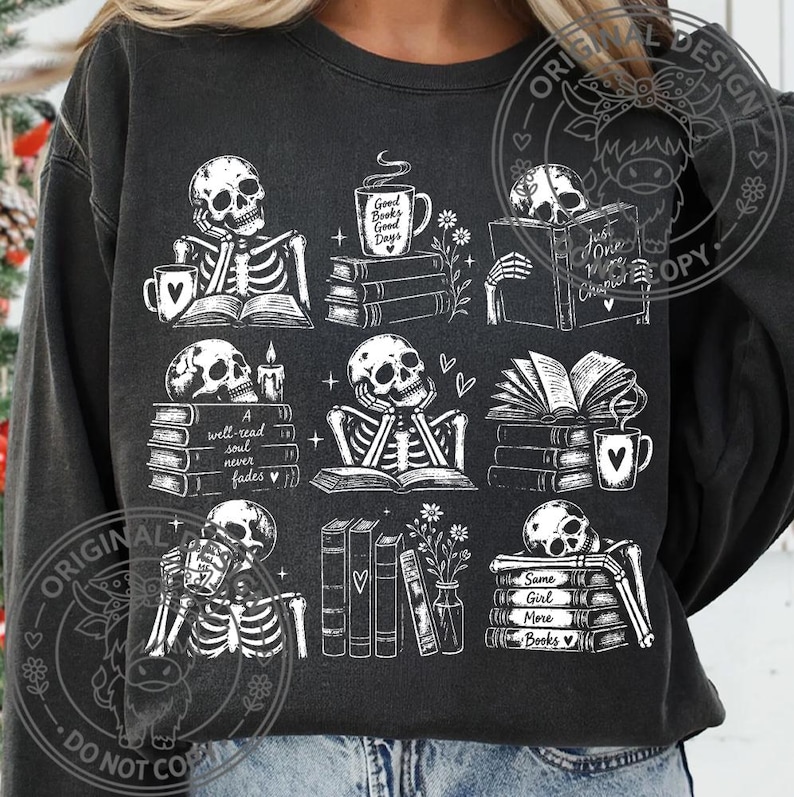 May include: A charcoal gray crewneck sweatshirt featuring a white graphic print of nine distinct scenes with skeletons reading books, drinking from mugs, and flowers. The text includes phrases like Good Books Good Days and A well-read soul never fades.