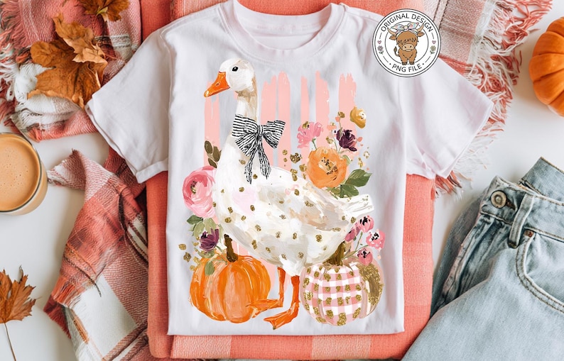 May include: White t-shirt featuring a goose illustration with a black bow, surrounded by flowers and pumpkins. The design includes gold polka dots and the text "Original Design PNG File".