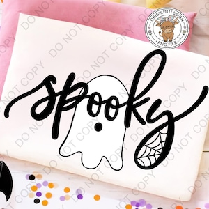 Op de afbeelding: Een wit t-shirt met een zwart grafisch ontwerp met het woord spooky in een cursief lettertype. De letter o is vervangen door de omtrek van een spookje en de letter y bevat een spinnenwebpatroon aan de onderkant van de staart.