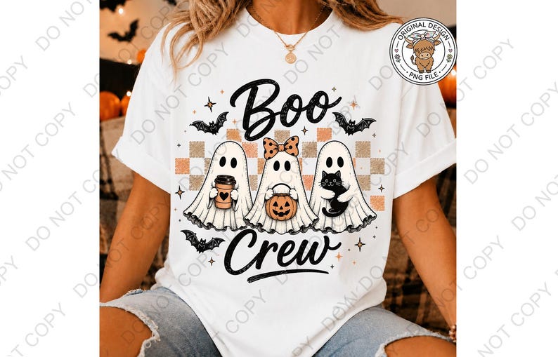 May include: A white t-shirt featuring a graphic of three ghosts with the text "Boo Crew". The ghosts are positioned over a checkered pattern and are accompanied by bats, a coffee cup, a pumpkin bucket, and a black cat. The design includes stars.