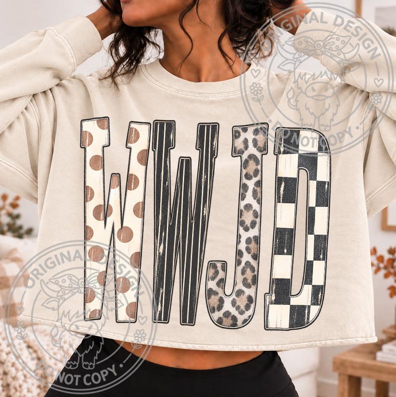May include: A beige long-sleeve sweatshirt featuring the letters WWJD in a large graphic print. Each letter has a distinct pattern: the Ws feature brown polka dots and black vertical stripes, the J has a leopard print, and the D has a black checkerboard.