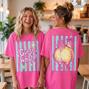 May include: Two women wearing matching pink t-shirts. The front of the shirt says "Guess What?" with stars. The back of the shirt features a cartoon chicken design with a pink bow and necklace, set against blue and pink stripes.
