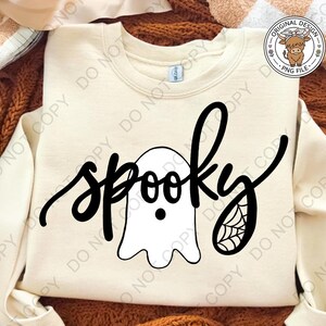 Op de afbeelding: Een cr&egrave;mekleurig sweatshirt met ronde hals en een zwarte grafische print. Het ontwerp toont het woord spooky in een cursief lettertype, waarbij een witte spookillustratie de letter o vervangt en een spinnenwebdetail op de letter y staat.