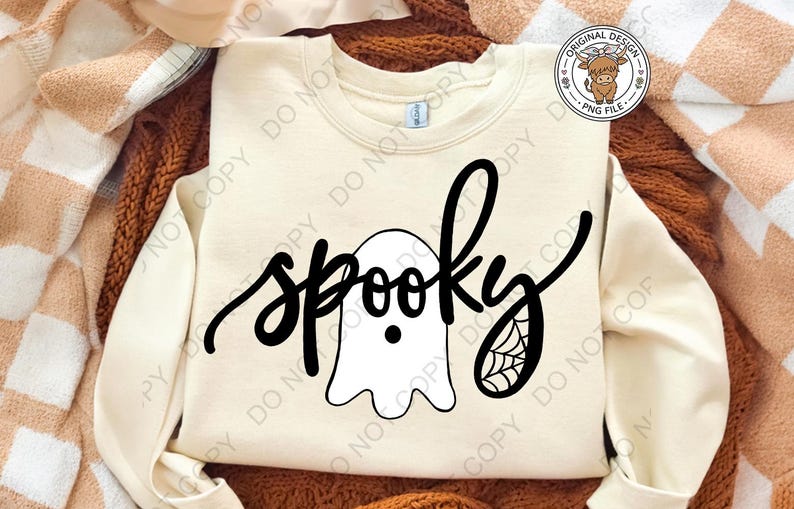 Op de afbeelding: Een cr&egrave;mekleurig sweatshirt met ronde hals en een zwarte grafische print. Het ontwerp toont het woord spooky in een cursief lettertype, waarbij een witte spookillustratie de letter o vervangt en een spinnenwebdetail op de letter y staat.
