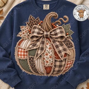 May include: A navy blue crewneck sweatshirt featuring a large, central graphic of a patchwork pumpkin. The pumpkin is composed of various fabric patterns including plaid, leopard print, floral, and stripes, accented with a frayed brown gingham bow.