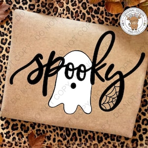 Op de afbeelding: Een rechthoekig bruin oppervlak met een zwarte scriptafbeelding met de tekst spooky. De letter o is vervangen door een wit spookje met een zwarte stip als oog, en de letter y eindigt in een zwart spinnenwebontwerp. Er is een rond logo aanwezig.